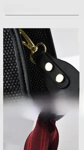 Detail of gold metal lobster clasp with striped canvas strap and black lychee leather