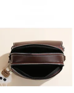 Detailed top view of dark brown crossbody bag showing three layered zipper compartments