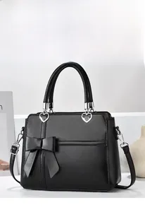 Detail of black leather handbag with bow decor and heart-shaped silver metal hardware