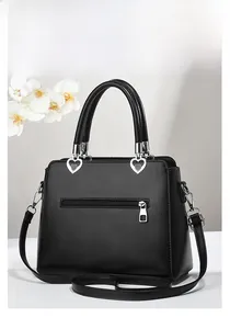 Close-up of black PU leather handbag with heart-shaped silver buckles and long strap