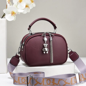 Burgundy litchi leather handbag with metal handle, wide strap and bear charm