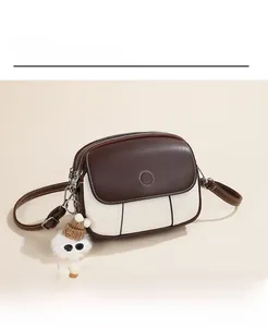 Close-up of contrast crossbody bag with white stitching and plush doll charm detail