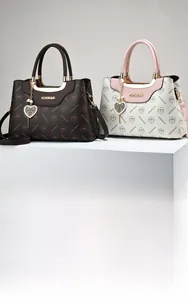Detail of printed leather handbags in dark brown and beige with heart-shaped metal charms