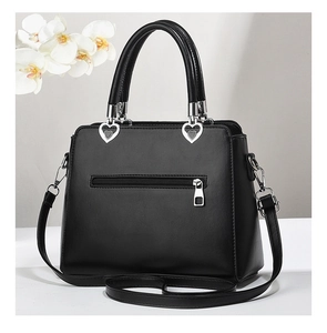 Detail of black leather handbag back zipper pocket and silver heart-shaped metal buckles