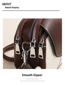 Detail of side view showing three-layer silver zippers on brown and beige crossbody bag