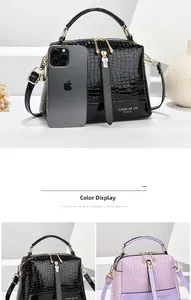 Detail der glänzenden Handtasche mit Krokodilmuster in Schwarz und Lila mit Golddekor