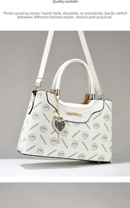 Detail view of white cowhide leather handbag featuring floral print and gold hardware