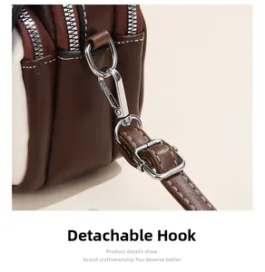 Detail of contrast leather handbag featuring silver metal hooks and adjustable strap