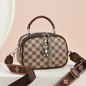 Sac à main monogramme tendance avec large bandoulière et breloque ours sur socle blanc