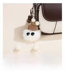 Detail of cute knitted cartoon pendant with sunglasses on a contrast color handbag