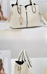 Detail einer weißen Handtasche mit vertikaler Textur, Hasenanhänger und langem Schultergurt
