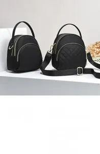 Close-up of dual black nylon crossbody bags featuring quilted patterns and gold metal zippers