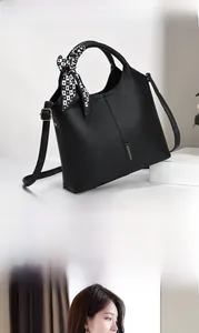 Detail of black lychee leather handbag with heart print silk scarf and gold fashion label