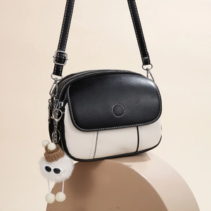 Stylish black and white contrast crossbody bag with a cute plush doll charm on base