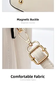 Detail der hellbeigen Ledertasche mit goldenen Bodennägeln und Metallriemen-Schnallen