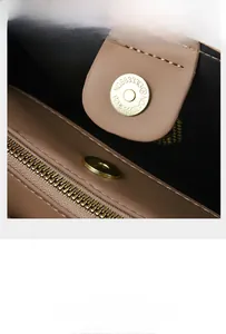 Macro detail of the golden magnetic closure and leather texture on an elephant grey handbag