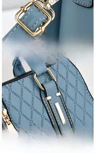 Detailed close-up of golden metal buckle and reinforced handle on blue embossed handbag