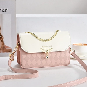 Sac à bandoulière rose et beige avec breloque aile dorée et texture matelassée sur socle