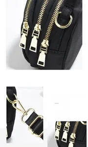 Détail du sac bandoulière noir montrant trois fermetures éclair et pièces métalliques dorées