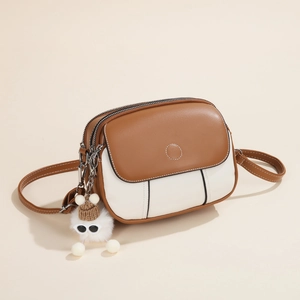 Two-tone contrast shoulder bag in brown and cream with a cute plush doll charm