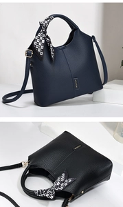 Detail of color-block satchel featuring litchi leather, silk scarf handle, and metal logo