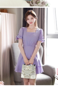 White vintage print handbag with gold ring handles shown with a light purple dress