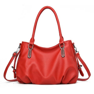 Red pebbled leather tote bag with round handles and adjustable shoulder strap on white base