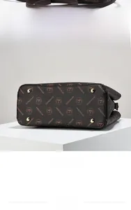 Detailed view of the dark brown patterned handbag base with four golden protective studs