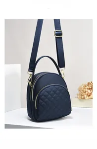Close-up of dark blue quilted handbag showing three zipper layers and gold hardware