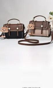 Détail de sacs à main en similicuir bicolore avec rabat ondulé et fermoir tournant en métal