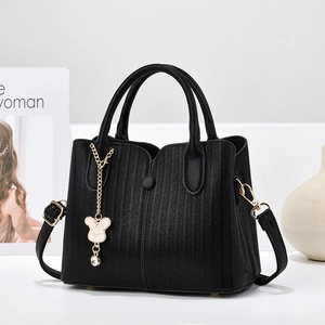 Elegant black textured leather handbag with gold bear pendant and dual carrying straps