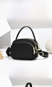 Détail du sac bandoulière noir multicouche en nylon avec fermetures dorées