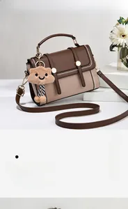 Détail du sac à main bicolore avec boucle métallique et pendentif ours en peluche
