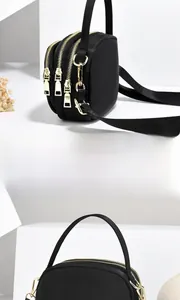 Vue latérale du sac bandoulière en nylon noir avec trois compartiments à zip doré