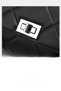 Close-up of black quilted leather texture and silver rectangular twist lock closure