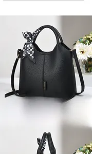 Macro view of black lychee grain leather handbag with stylish printed silk scarf detail