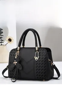 Macro detail of black litchi grain leather bag with V-shaped stitching and gold hardware