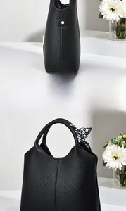 Detail of black lychee grain texture handbag featuring a stylish checkered silk scarf accent