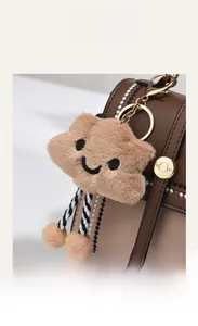 Gros plan des coutures contrastées du sac en cuir avec charm nuage en peluche