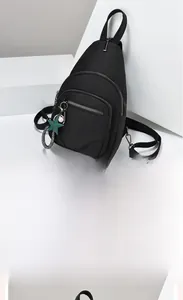 Detail of black nylon chest bag with multi-zipper pockets and star pearl pendant charm