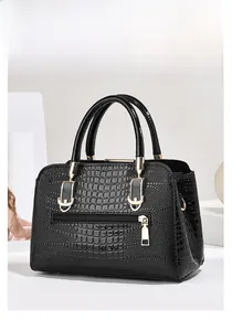 Detail of black crocodile texture handbag with golden hardware and front zipper pocket