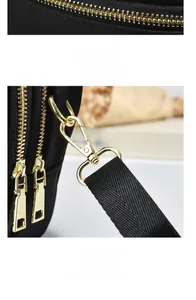 Close-up of golden metal zippers and detachable swivel hooks on black nylon bag