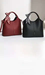 Detail of lychee pattern leather handbag with scarf handle and fashion logo tag