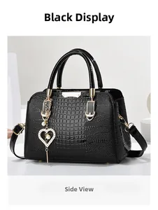 Detail view of black crocodile pattern handbag with golden heart pendant and dual handles