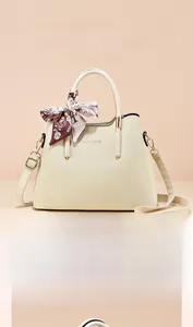 Detail of elegant beige leather handbag with a floral silk scarf wrapped around the handle