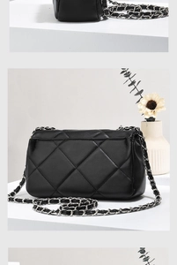 Detail of the black quilted mini bag with silver-tone metal and leather chain strap