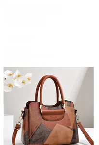 Close-up of color-block tote bag with leather tag, dual handles and metal hardware