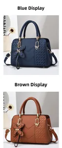 Detail view of blue and tan litchi leather handbags with V-shaped stitching and gold charms