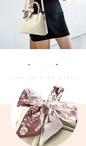 Detail of beige leather bag featuring lychee texture and silk scarf accessory on handle