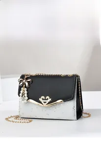 Detail of crossbody bag with golden heart buckle, star sequins, and pearl bow charm